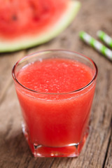 Refreshing watermelon juice on rustic wood (Selective Focus, Focus on the front of the glass rim)