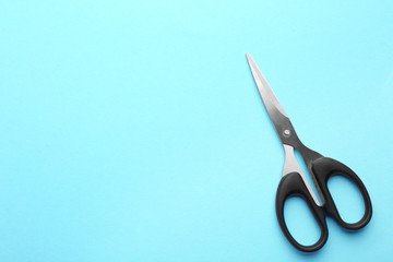 Pair of sharp scissors on color background, top view. Space for text
