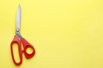 Pair of sharp scissors on color background, top view. Space for text