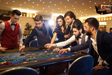 Rich friends make bets gambiling at the roulette table in the casino.