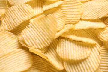 Pile of crispy potato chips as background, closeup