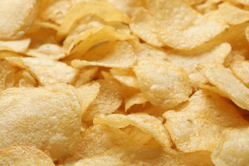Pile of crispy potato chips as background, closeup