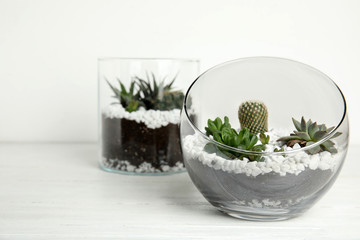 Glass florarium with different succulents on wooden table against white background, space for text