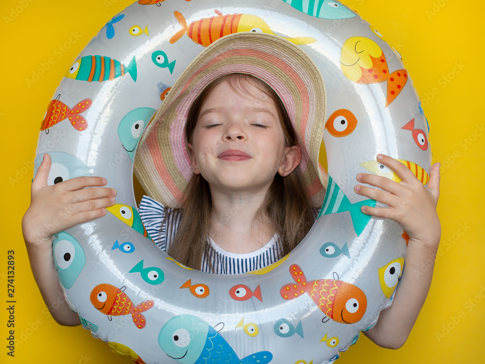 Wall mural summer portrait of a beautiful little cute toothless girl in a hat and dress- holding an inflatable 