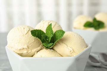 Delicious vanilla ice cream with mint in bowl on table, closeup