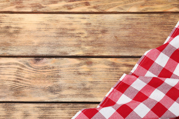 Checkered picnic blanket on wooden background, top view. Space for text