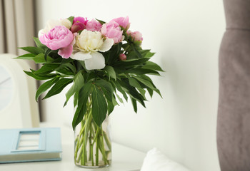 Vase with bouquet of beautiful peonies on table in room, space for text