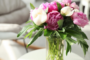 Vase with bouquet of beautiful peonies in room