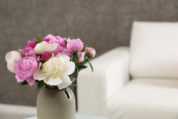 Vase with bouquet of beautiful peonies in room, space for text