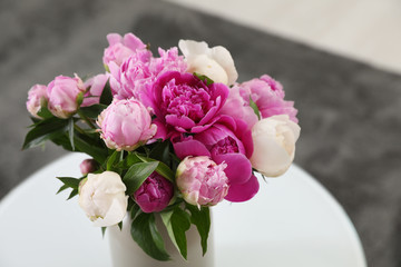 Vase with bouquet of beautiful peonies on table in room, space for text