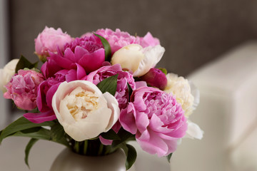 Vase with bouquet of beautiful peonies in room, closeup
