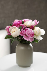 Vase with bouquet of beautiful peonies on table in room
