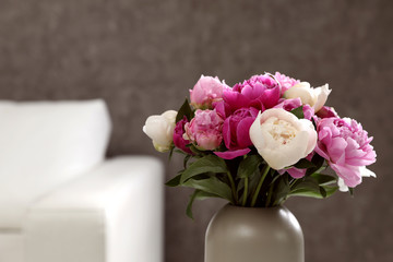 Vase with bouquet of beautiful peonies in room, space for text