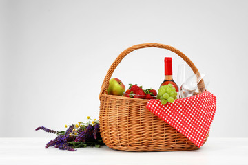 Picnic basket with wine, glasses and products on white background