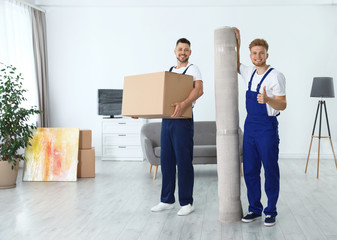 Fototapeta na wymiar Moving service employees with box and carpet in room