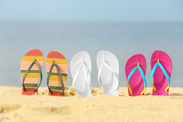 Different bright flip flops in sand. Beach accessories