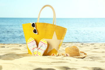 Composition with stylish beach accessories on sand near sea