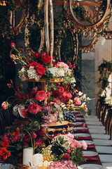 Wedding table flowers with fruits and berries gold decoration in red white pink green colors.