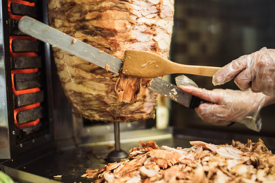 Cooking Shawarma And Ciabatta In A Cafe. A Man In Disposable Gloves Cuts Meat On A Skewer.