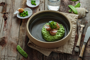 Scallops with pea puree on wooden background, rustic style