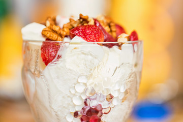 Vanilla ice cream with strawberry and walnut in bowl on blurred background