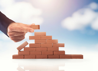 Businessman puts a brick to build a wall. Concept of new business, partnership, integration and...