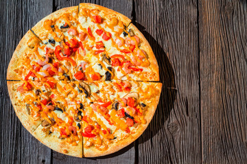 Top view delicious fresh pizza with shrimps, mushrooms and cheese close