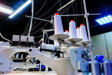 bobbins with white threads secured in an industrial sewing machine