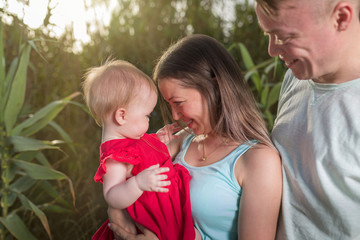 Happy family outdoor. Parents hold child on hands and rejoice. They are happy together