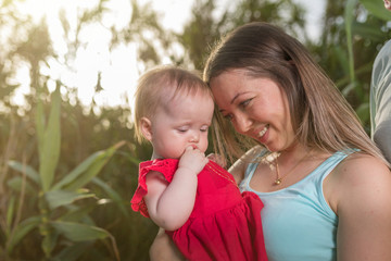 Happy family in the park evening light. The lights of a sun. Mom, dad and baby happy walk at sunset. The concept of a happy family