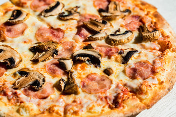 Delicious fresh pizza with salami, mushrooms and cheese close up in paper box