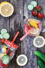 Lemonade with a strawberry, lemon, cucumber in glass jars on wooden background. copy space