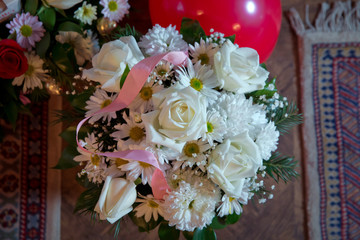 Connected with a pink ribbon . Handmade hite bouquet Rose In Love hart Shape Valentine in close-up . White Bouquet .