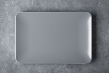 Gray empty rectangular plate over concrete background.