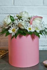 Flower arrangement in a hat box , a pot of pink for a girl on a gift with roses . White and yellow flower pink round bouquet .