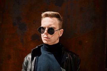 portrait of a handsome young man in sunglasses on a rusty iron background