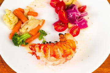 Lobster Tail Dinner with Steamed Vegetables and Pickled Tomatoes and Purple Onions on White Plate