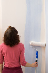 Woman applying paint on wall