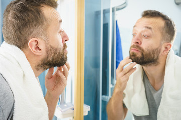 Man looking at his beard in mirror