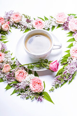 Wedding floral arrangement. Frame of flowers in heart-shaped: rose, lilac, rowan leaves and cup coffee on a white background. Floral pattern.