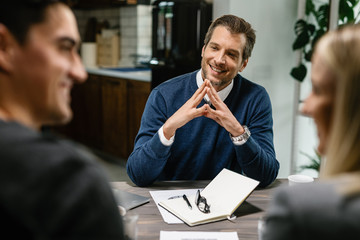 Happy insurance agent having a meeting with a couple at their home.