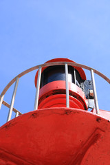 Close up of a coastal viewing platform with a warning light for shipping. Painted a bright coastal red against a deep blue summer sky. Could be used as a coastal home interior picture.