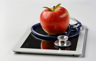 Medical content. Research. Science. Diagnostic. Treatment. Medical stethoscope and red apple lying on a tablet isolated on white background. Copy space for your text. Close up photo.