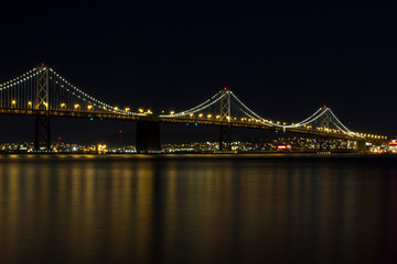 Fototapeta na wymiar Bay Bridge reflecting on the ocean at night in San Francisco California