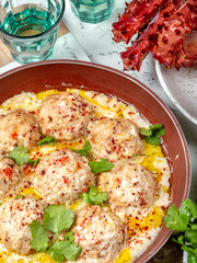 CRABMEATBALLS crab meatballs in white creamy sauce in red pan, whole king crab, cilantro, lemon and white wine on white background