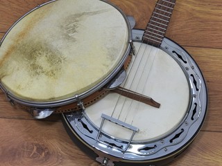 Two Brazilian musical instruments: samba banjo (strings) and pandeiro (tambourine) on a wooden surface. They are widely used to accompany samba, the most famous Brazilian rhythm.