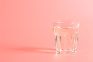 glass of water on a pink background.