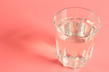 glass of water on a pink background.