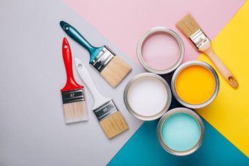 Four open cans of paint with brushes on bright background.