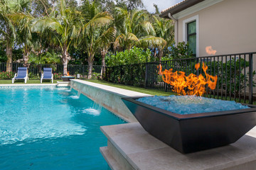Gas fire pit next to a pool with waterfall
